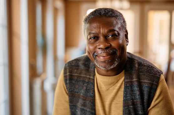 Closeup of man in plaid vest smiling at home