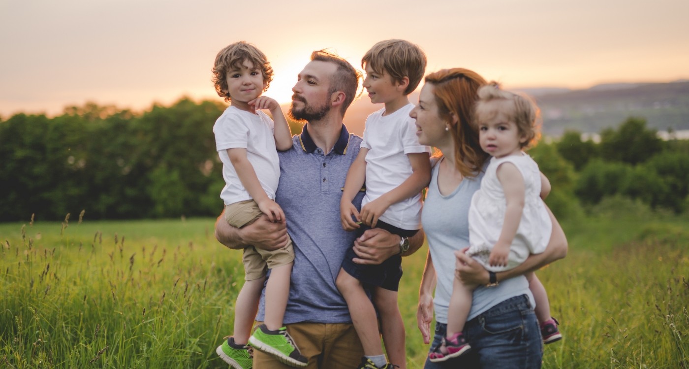 Family of five smiling outdoors after receiving dental services in Worcester