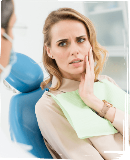 Woman holding her cheek in pain while talking to emergency dentist