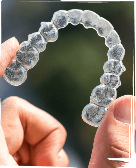 Hand holding an Invisalign clear aligner outdoors