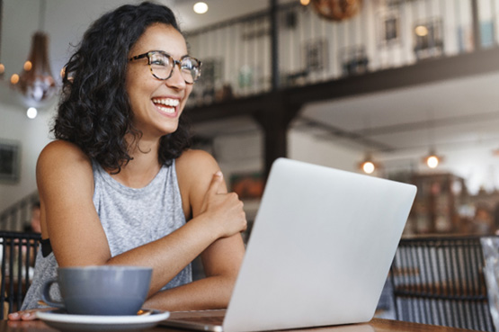 Woman smiling while working on laptop in coffee shop