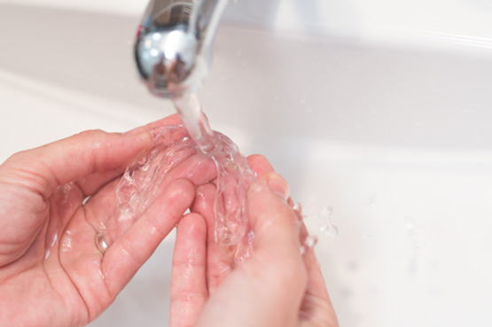 Patient rinsing clear aligners in sink