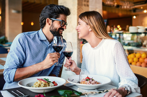 Couple smiling at each other while enjoying meal at restaurant