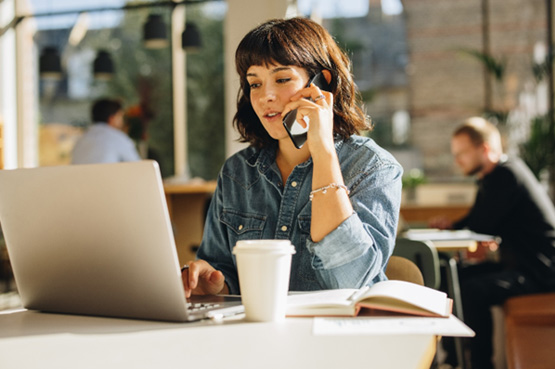 Woman talking on phone while working on laptop