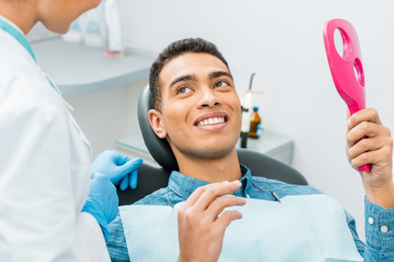 Patient smiling at dentist with pink mirror
