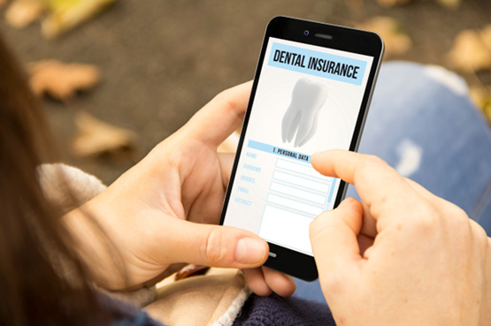 Patient looking at dental insurance form on phone outside
