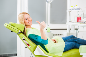 a patient at their dentist giving a thumbs up