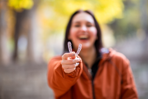 a person holding their Invisalign aligner and smiling